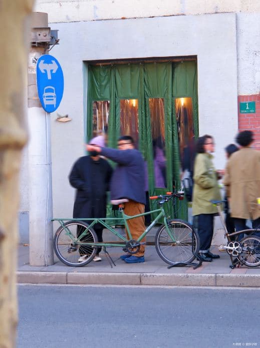 Grüner Eingang von Slab Town an der Fumin Road mit Gästen und Fahrrädern